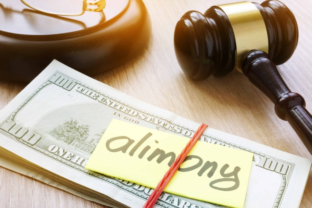Alimony payment concept with gavel, stack of hundred dollar bills, and note labeled alimony.