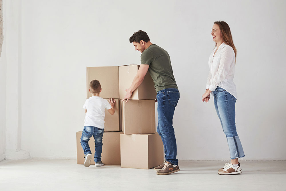 Family unpacking moving boxes in a new home with a child helping
