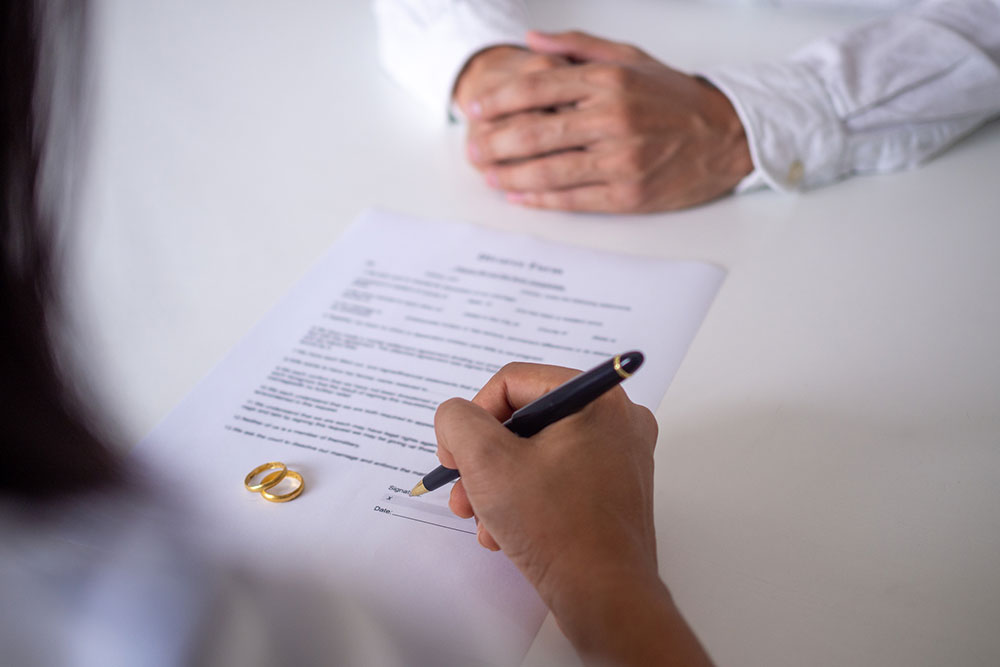 Person signing divorce documents with a pen