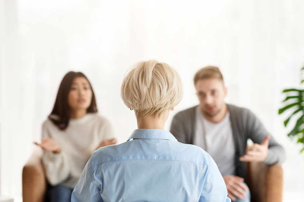Two people speaking with a neutral professional in an office setting