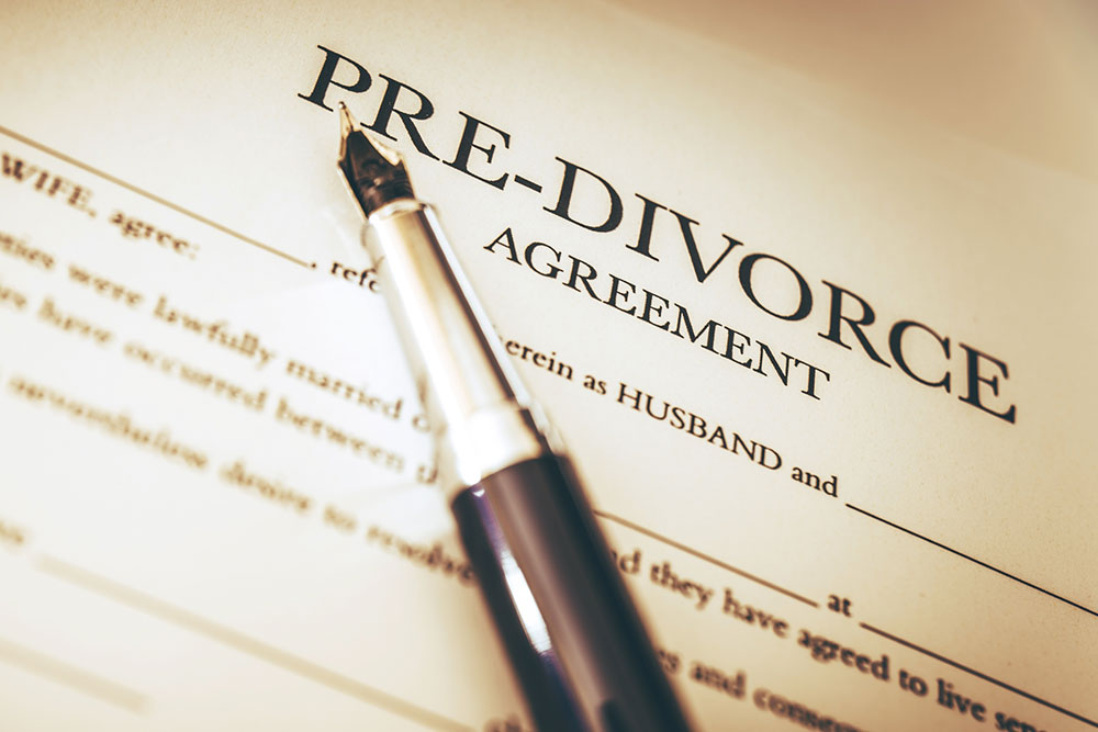 Hands signing legal documents on a desk