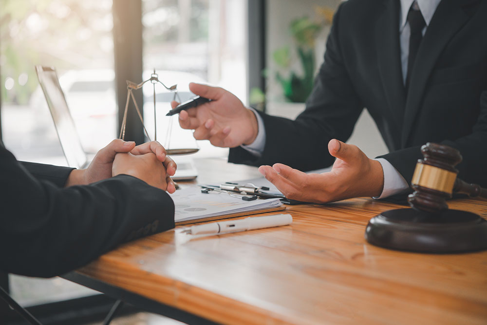 Two people meeting with a lawyer to review documents and agreements